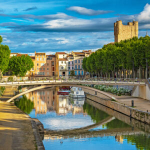 a bridge over a canal with trees and buildings