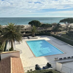 a swimming pool with palm trees and a beach in the background