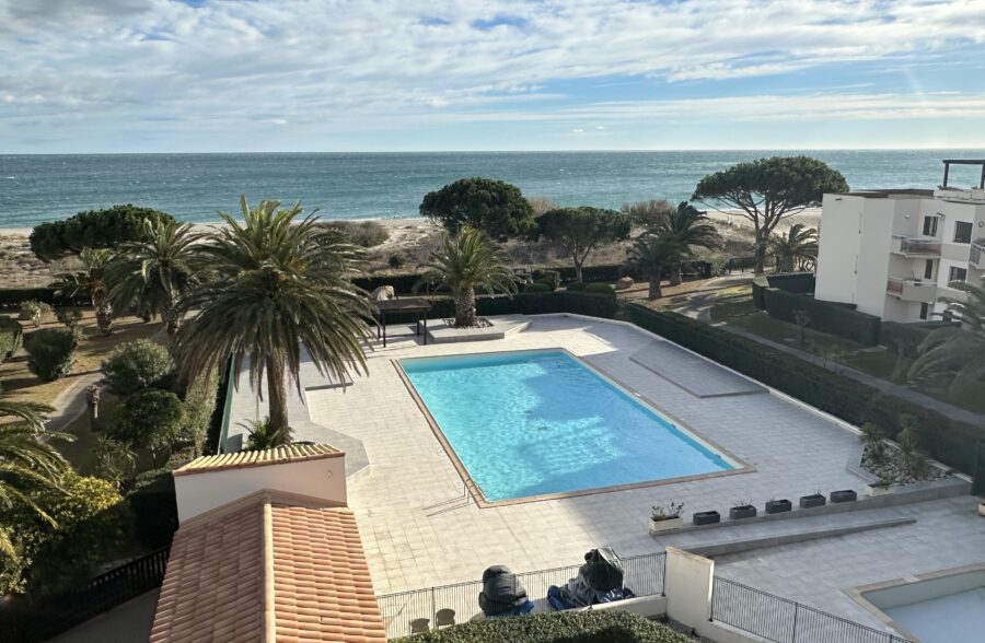 a swimming pool with palm trees and a beach in the background